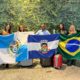 estudantes e professores do Colégio Estadual Marechal Zenóbio sorrindo com as bandeiras do Estado do Rio de Janeiro, da cidade de Nilópolis e do Brasil
