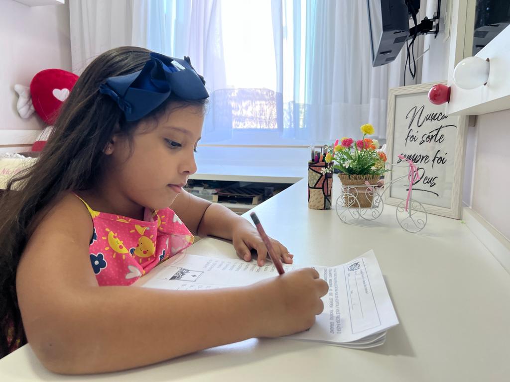 Nicolle de Paula Peixoto, de 8 anos, fazendo dever de casa