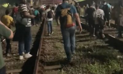 Passageiros andam no trilho do trem
