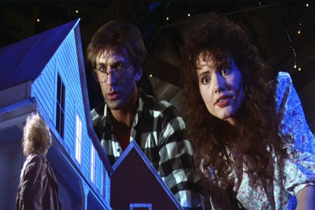 Casal olhando uma maquete de uma casa e um homem miniatura nela