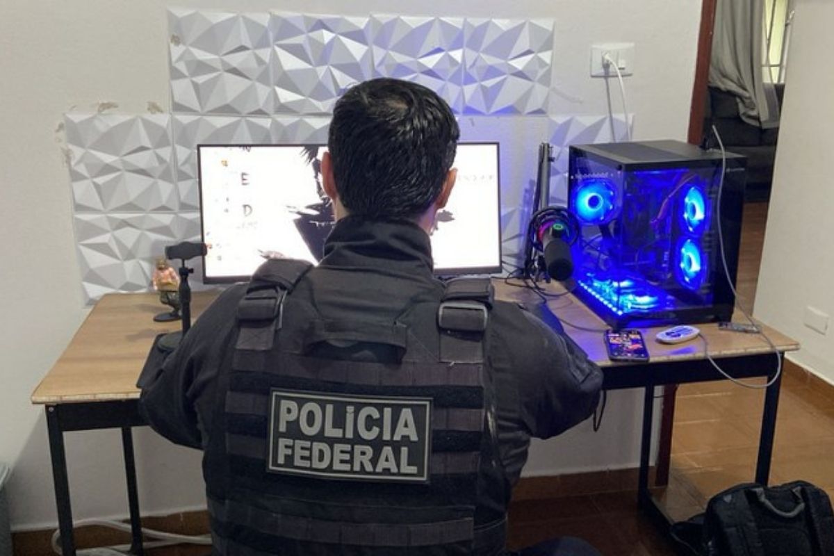 agente da Polícia Federal sentado à frente de um computador.