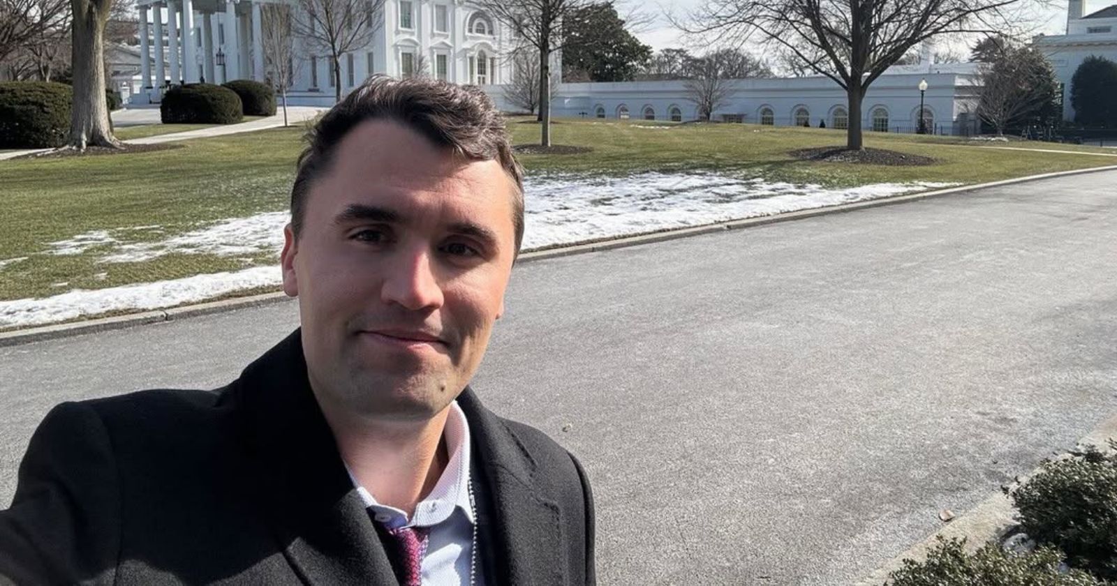 Homem tira selfie próximo à Casa Branca em dia frio, com neve espalhada pelo gramado