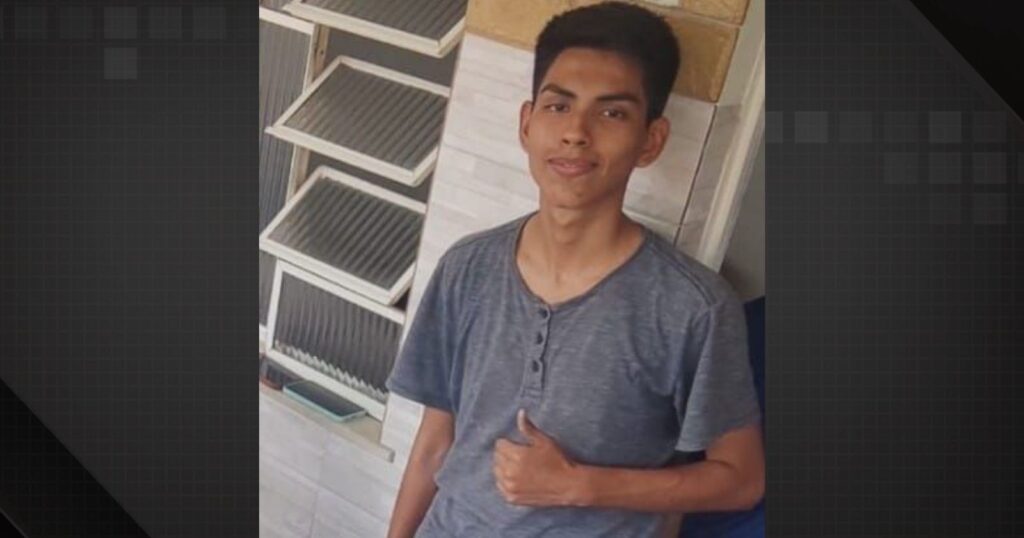 João Zurita, adolescente de 17 anos desaparecido, veste camisa cinza e posa sorrindo com sinal de positivo