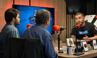FuiClear sentado à mesa do estúdio da Rádio Tupi durante gravação do Penido's Podcast com Rafa e Luiz Penido
