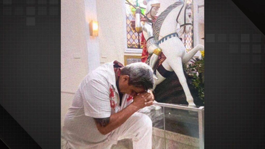 Homem ajoelhado em oração diante da imagem de São Jorge em igreja