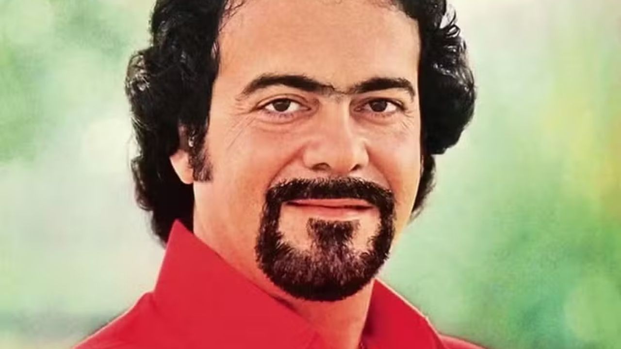 Close-up de Lindomar Castilho sorrindo, com cabelo escuro cacheado, monocelha e barba estilo cavanhaque.