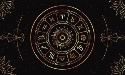 Roda astrológica dourada com símbolos do zodíaco e um sol central em fundo preto estrelado.