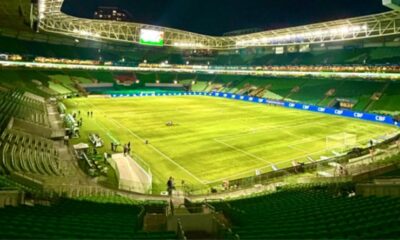 Visão noturna panorâmica do estádio Allianz Parque com campo iluminado e arquibancadas vazias.