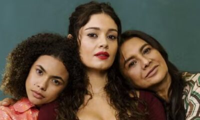 Atrizes Sophie Charlotte, Dira Paes e Alana Cabral, com cabelos escuros, sorrindo contra fundo verde.