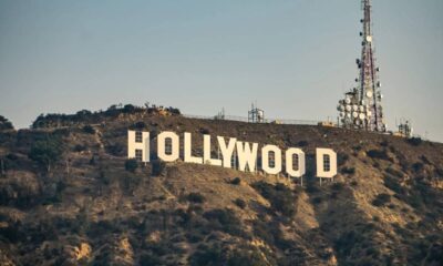 O famoso letreiro 'HOLLYWOOD' em uma colina ensolarada, com torre de comunicação ao lado.