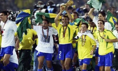 Jogadores brasileiros, com camisas amarelas, celebram vitória na Copa do Mundo com o troféu.