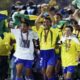 Jogadores brasileiros, com camisas amarelas, celebram vitória na Copa do Mundo com o troféu.