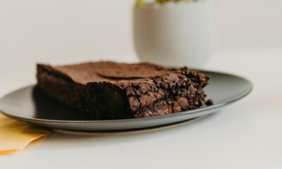 Pedaço de brownie de chocolate em prato cinza escuro, com guardanapo amarelo.