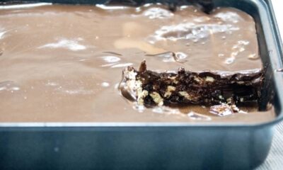 Palha italiana de chocolate em travessa preta, com um pedaço removido revelando biscoitos.