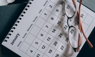 Página de calendário de janeiro com datas, óculos de armação clara sobre a folha.