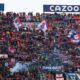 Multidão de torcedores do Bologna no estádio, com bandeiras e cachecóis vermelhos e azuis.