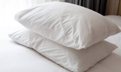 Dois travesseiros brancos e limpos estão empilhados sobre uma cama com lençóis brancos.