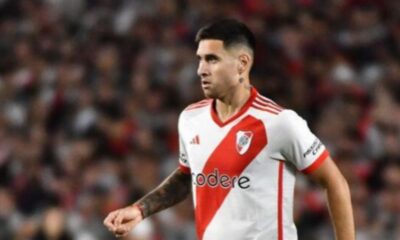 Jogador de futebol, camisa River Plate branca e vermelha, em campo.