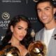 Georgina Rodríguez e Cristiano Ronaldo sorrindo, segurando troféus dourados, em evento Global Soccer.