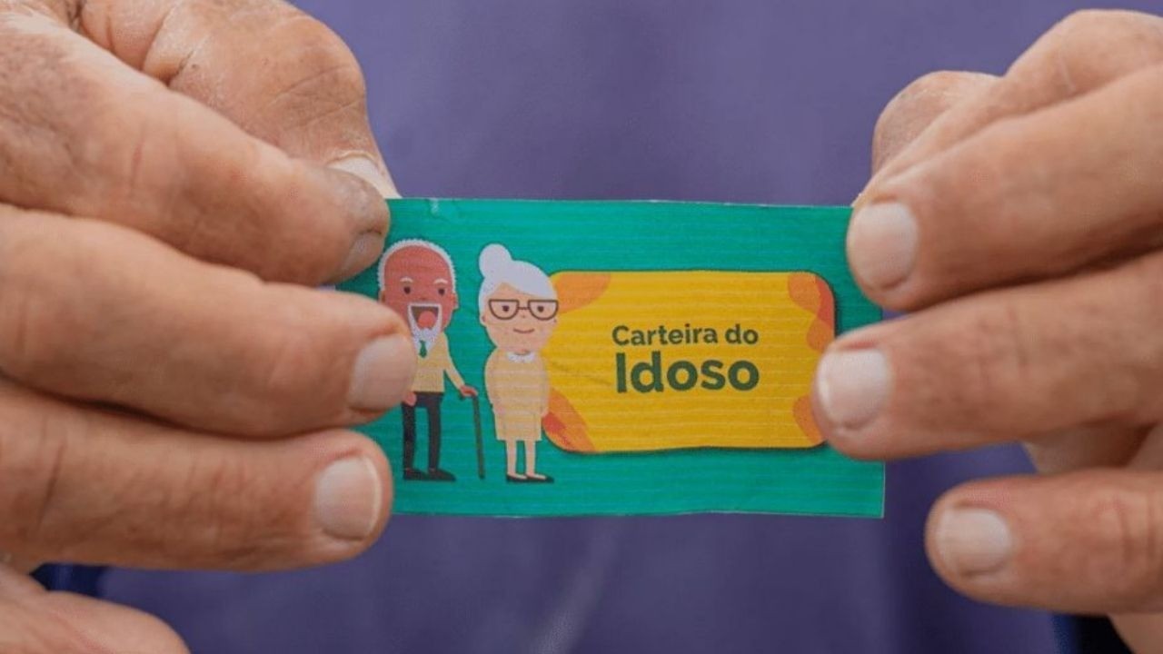 Mãos segurando a Carteira do Idoso, um cartão verde com ilustração de casal de idosos.