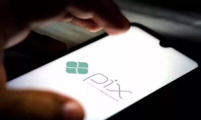 Mão segurando celular exibindo o logo Pix e 'Powered by Banco Central'.