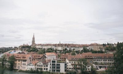 Vista panorâmica de cidade histórica suíça com edifícios de telhado vermelho, rio e torre de igreja.