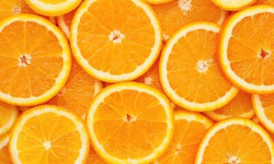 Close-up de muitas fatias de laranja frescas, com polpa laranja e bordas brancas.