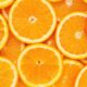 Close-up de muitas fatias de laranja frescas, com polpa laranja e bordas brancas.
