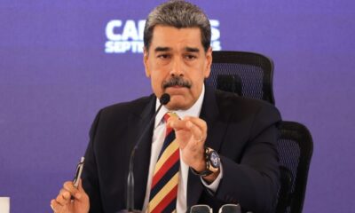 Nicolás Maduro, de terno escuro e gravata, discursando ao microfone, gesticula.