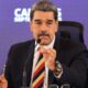 Nicolás Maduro, de terno escuro e gravata, discursando ao microfone, gesticula.