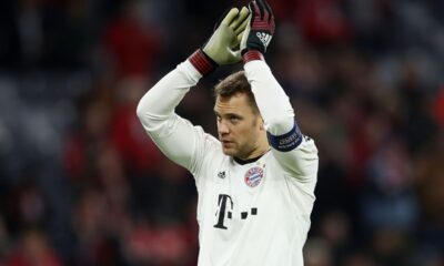 Manuel Neuer, goleiro do Bayern, aplaudindo, usando camisa branca e luvas verdes e vermelhas.