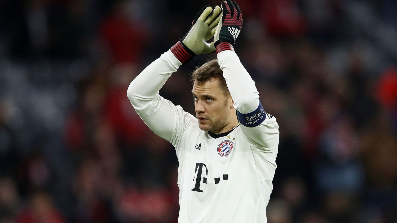 Manuel Neuer, goleiro do Bayern, aplaudindo, usando camisa branca e luvas verdes e vermelhas.