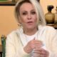 Ana Maria Braga, loira, gesticulando e falando em um estúdio com fundo claro e objetos decorativos.