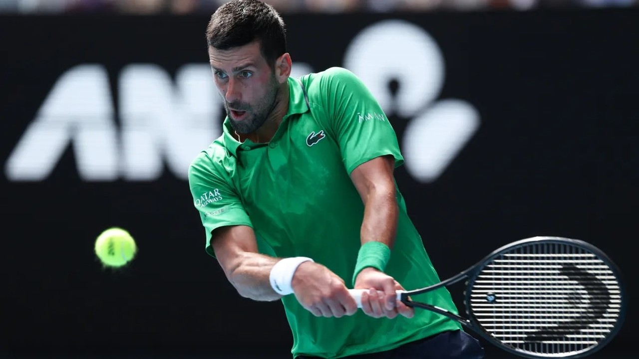 Novak Djokovic em quadra de tênis, com raquete e bola, logo borrado AN ao fundo.