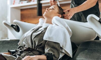Mulher tem cabelo lavado por cabeleireiro em lavatório branco de salão de beleza.