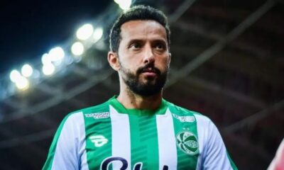 Jogador Nenê em campo, vestindo camisa listrada verde e branca de time de futebol.