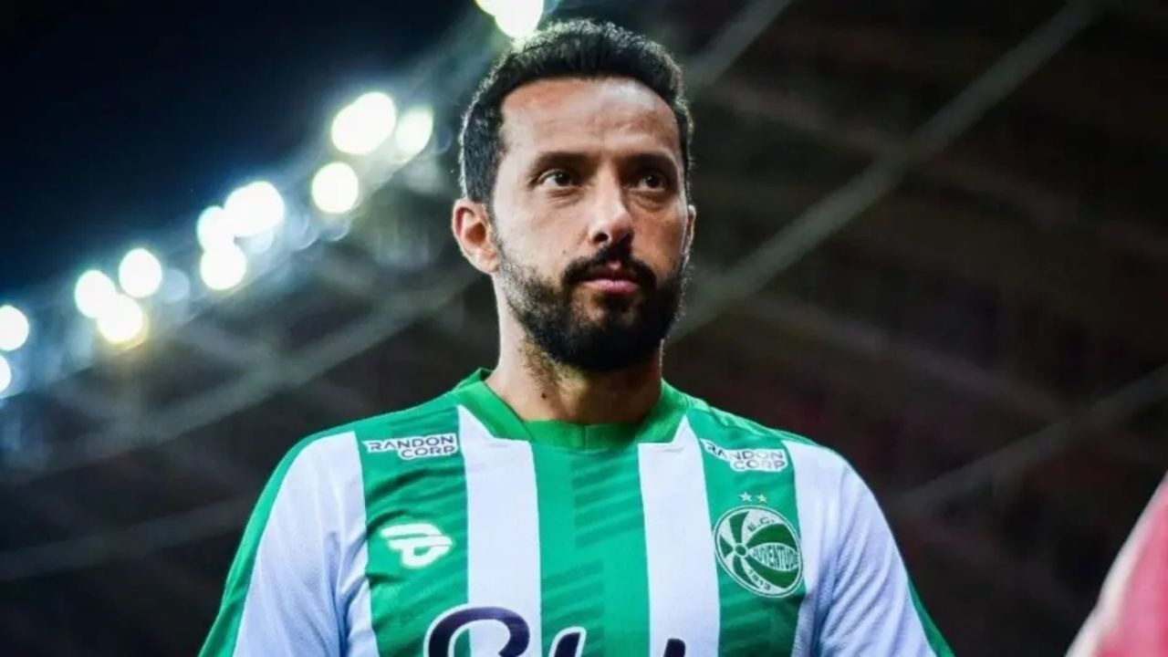 Jogador Nenê em campo, vestindo camisa listrada verde e branca de time de futebol.