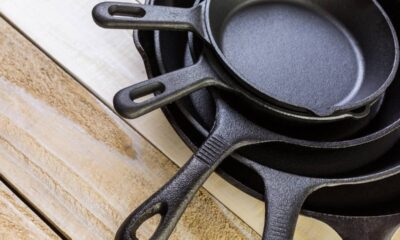 Pilha de frigideiras de ferro fundido pretas de diferentes tamanhos sobre uma superfície de madeira.