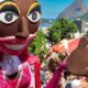 Boneco de Carnaval no meio da multidão, com Pão de Açúcar e cidade do Rio de Janeiro ao fundo.