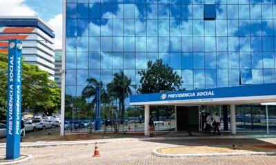 Fachada de vidro azul do edifício sede da Previdência Social (INSS) com letreiro.