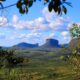 Vista panorâmica de montanhas de topo plano e vales verdes sob céu azul com nuvens.