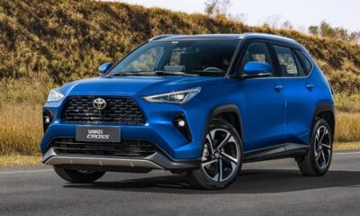 SUV Toyota Yaris Cross azul com teto preto em estrada, com paisagem seca e vegetação ao fundo.