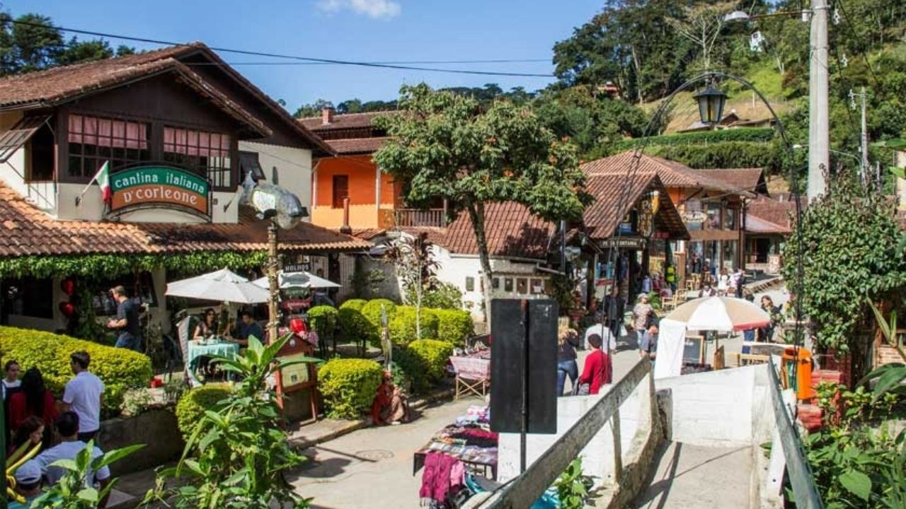 Rua com restaurante italiano 'Cantina Italiana D'Corleone', pessoas jantando ao ar livre e árvores.