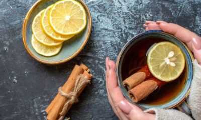 Mãos seguram xícara com limão e canela; prato com rodelas de limão e canela em pau.