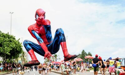 Gigante boneco do Homem-Aranha flutua sobre rua cheia de foliões em festa no Rio.
