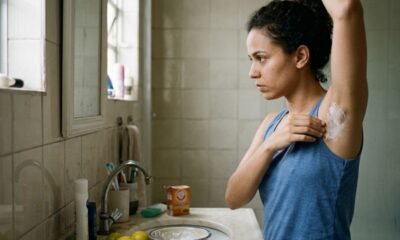 Mulher aplicando pasta branca na axila em um banheiro, com bicarbonato de sódio e limões.