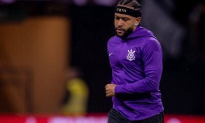 Memphis Depay com camisa roxa do Corinthians, headband e cabelo trançado, em campo.