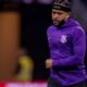 Memphis Depay com camisa roxa do Corinthians, headband e cabelo trançado, em campo.