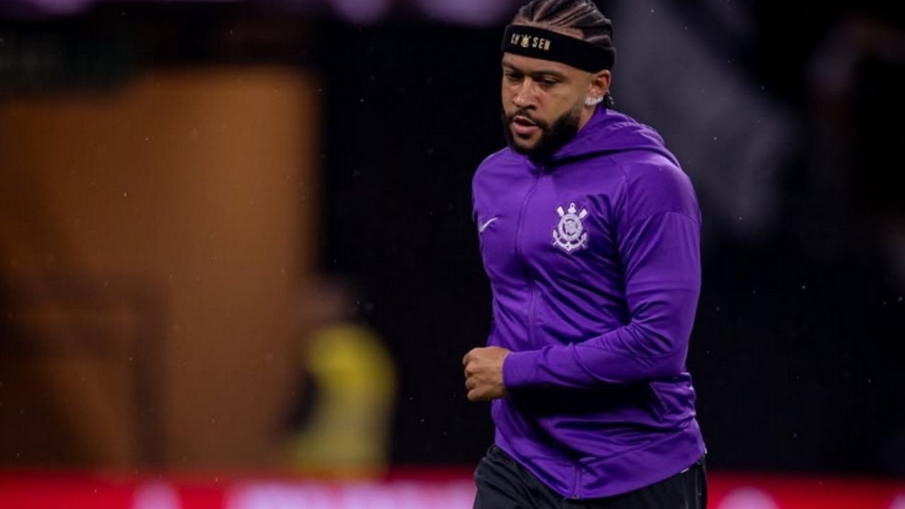 Memphis Depay com camisa roxa do Corinthians, headband e cabelo trançado, em campo.