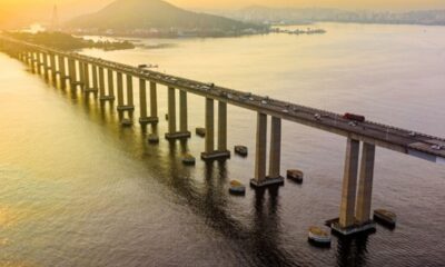 Vista aérea da Ponte Rio-Niterói com tráfego sobre a Baía de Guanabara ao pôr do sol.